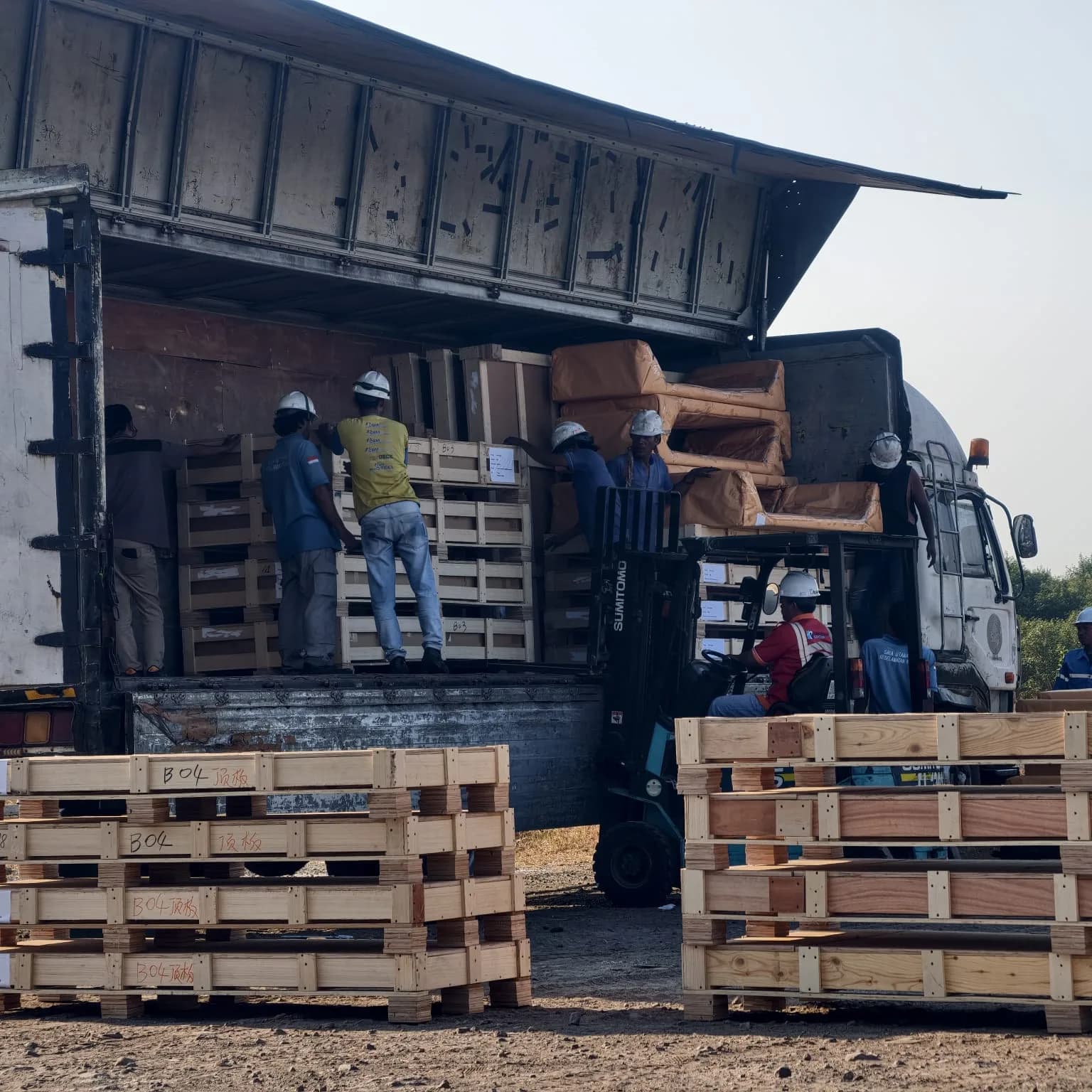 Tim dan forklift menangani peti kayu di sisi truk